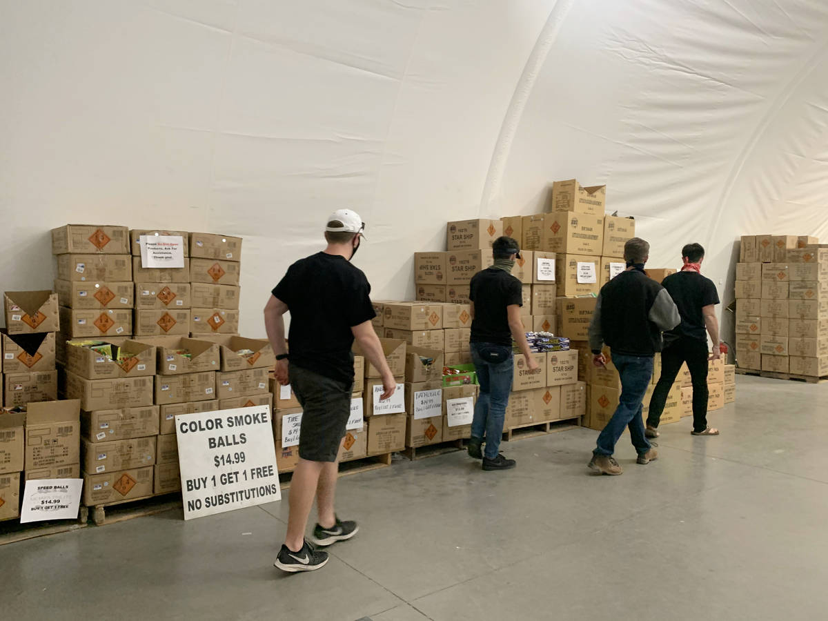 Individuals look at fireworks to purchase at Moapa Paiute Travel Plaza in Moapa on Tuesday, Dec ...