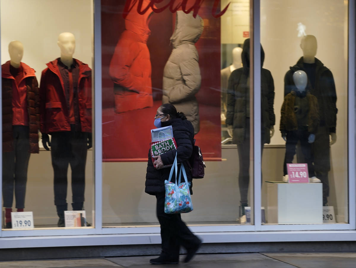 A pedestrian wears a mask while passing by a window display in a clothing store late Monday, De ...