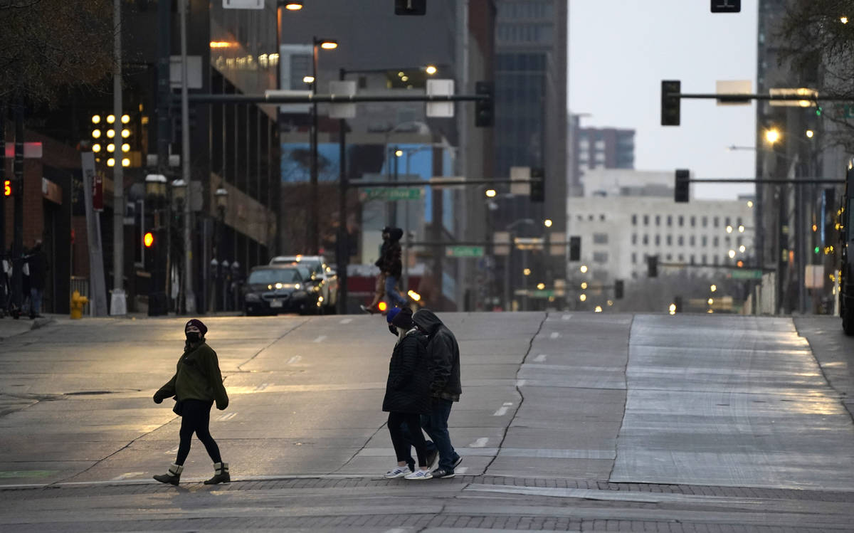 Pedestrians wear masks while crossing an empty road at the intersection of Market Street and 15 ...