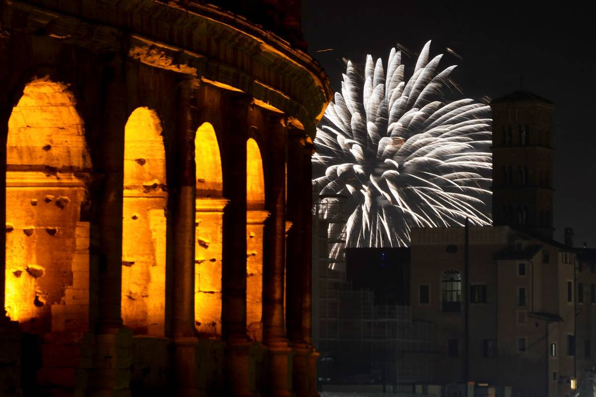 Fireworks explode in the sky next to Rome's Colosseum during New Year's celebrations, in Rome, ...