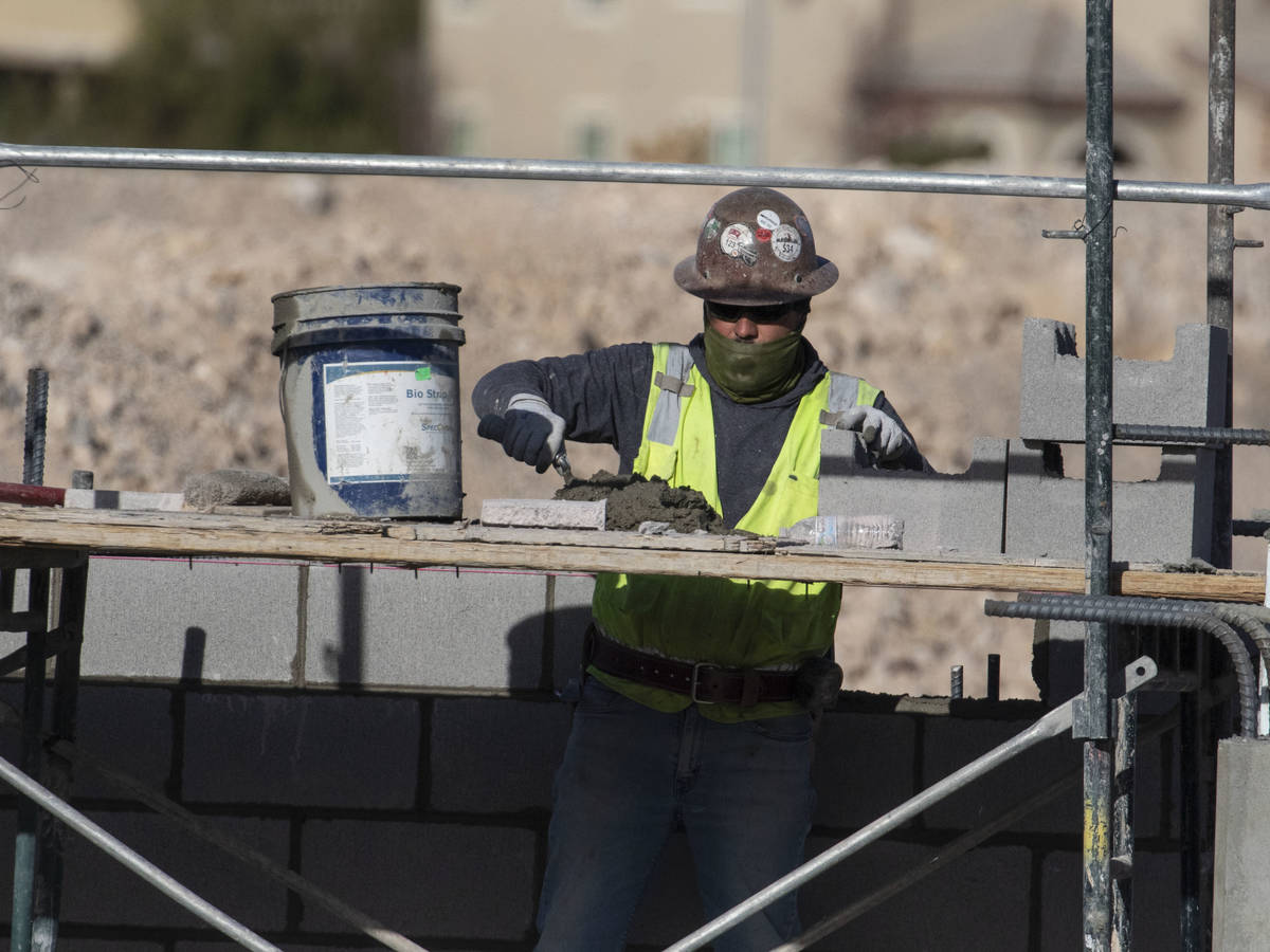 A construction worker lays blocks at the underground parking garage at the Evora apartment comp ...