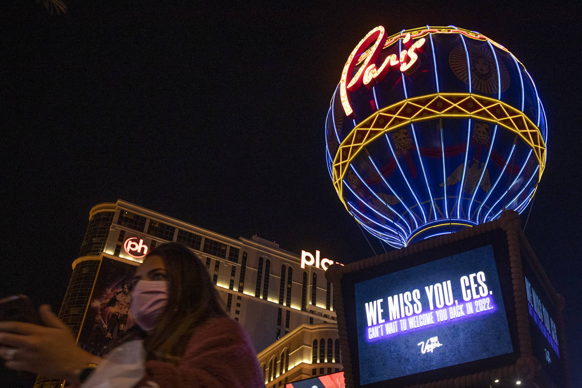 A masked pedestrian walks past a marquee at Paris that memorializes CES, which would have start ...