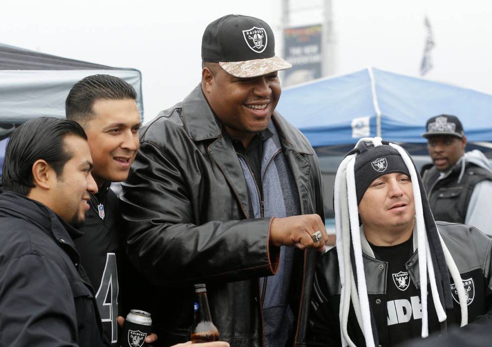 Former Oakland Raiders offensive lineman Lincoln Kennedy, center poses for photos with fans in ...
