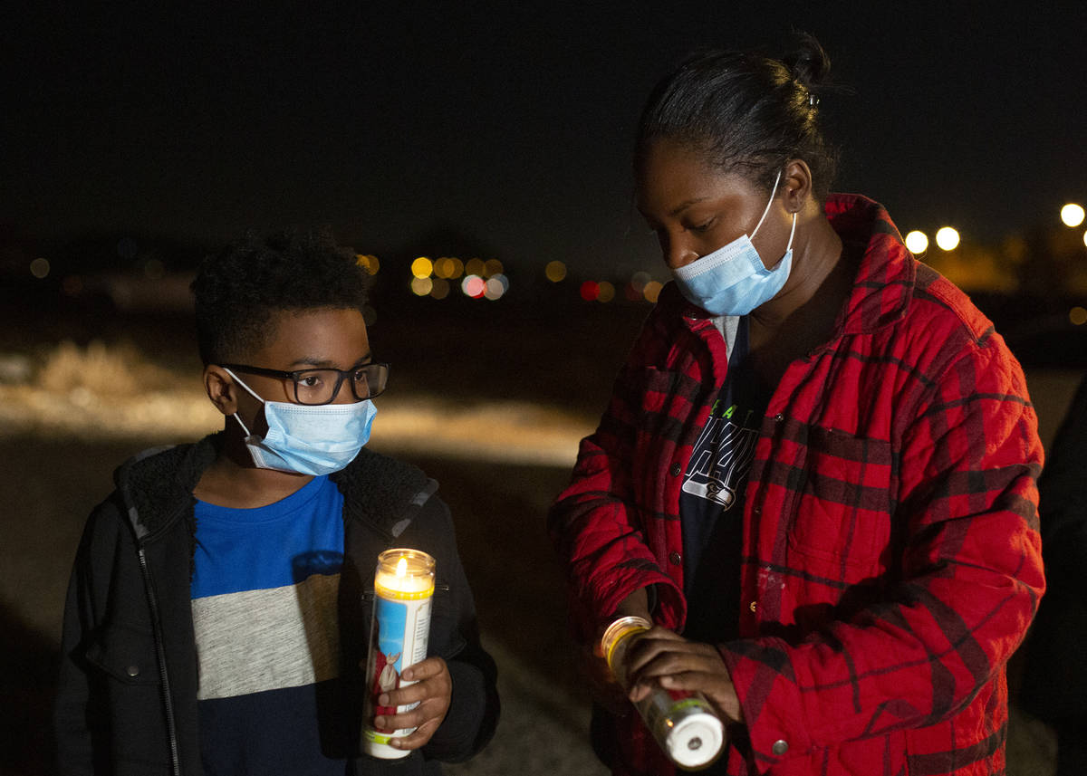 Jayden Felder, left, and his mother Ronita Felder light candles at a vigil for Eric Echevarria, ...