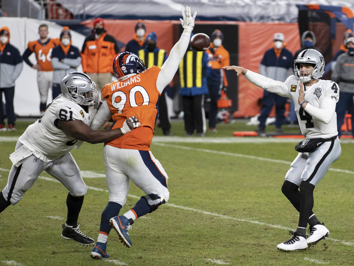 Raiders quarterback Derek Carr (4) makes a pass over Denver Broncos nose tackle DeShawn William ...