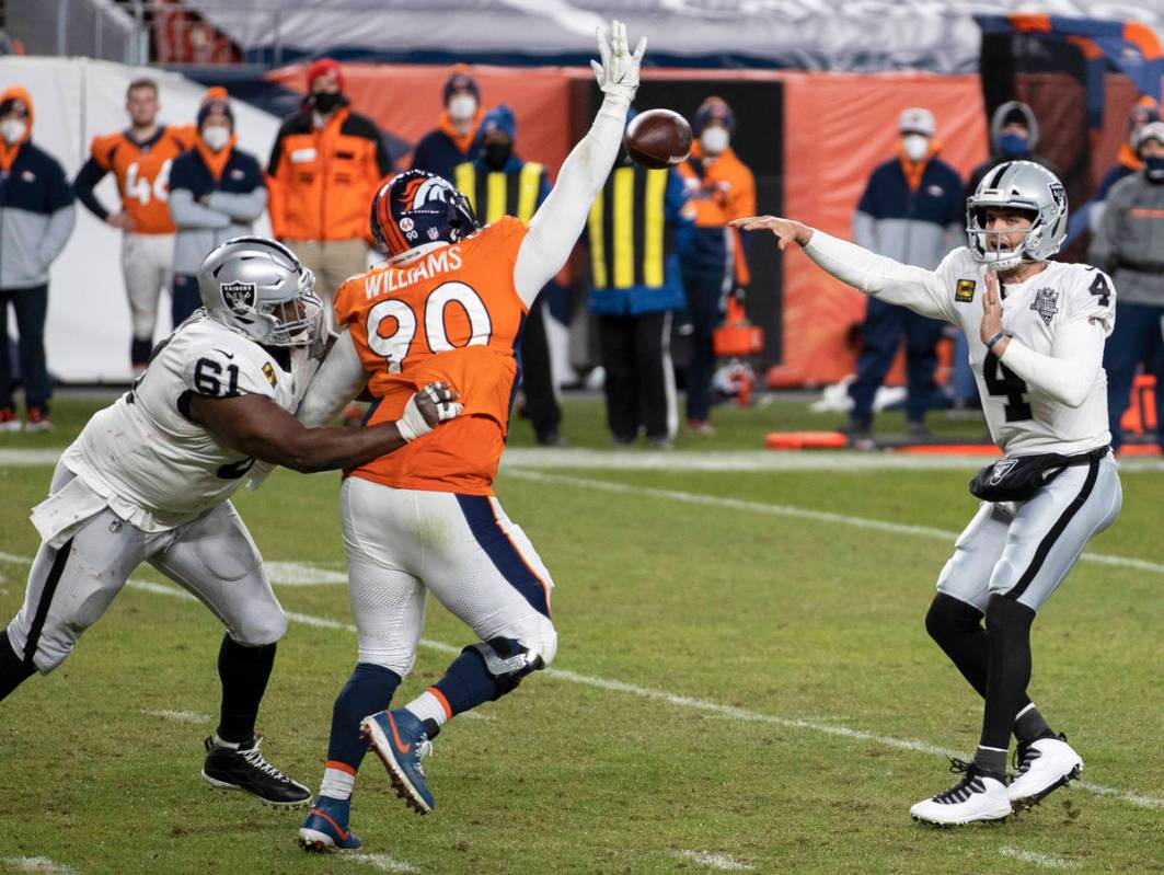 Raiders quarterback Derek Carr (4) makes a pass over Denver Broncos nose tackle DeShawn William ...