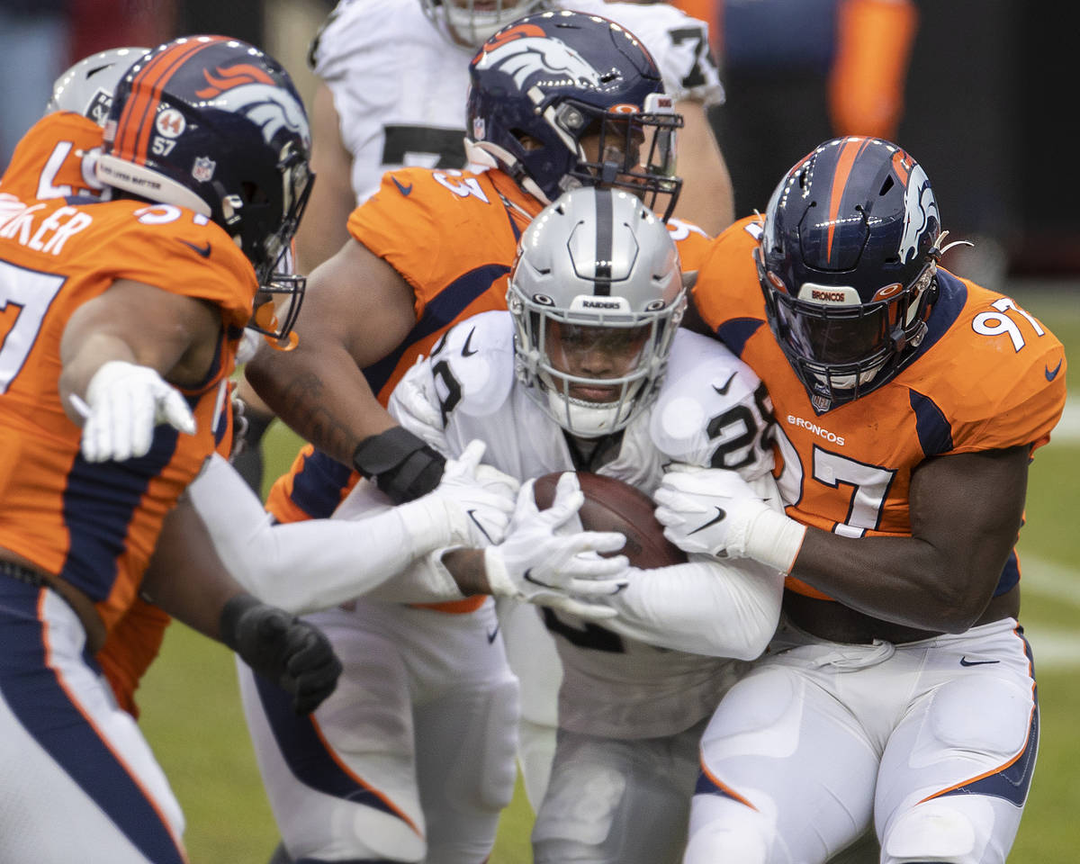 Raiders running back Josh Jacobs (28) is gang tackled by Denver Bronco defenders in the first q ...