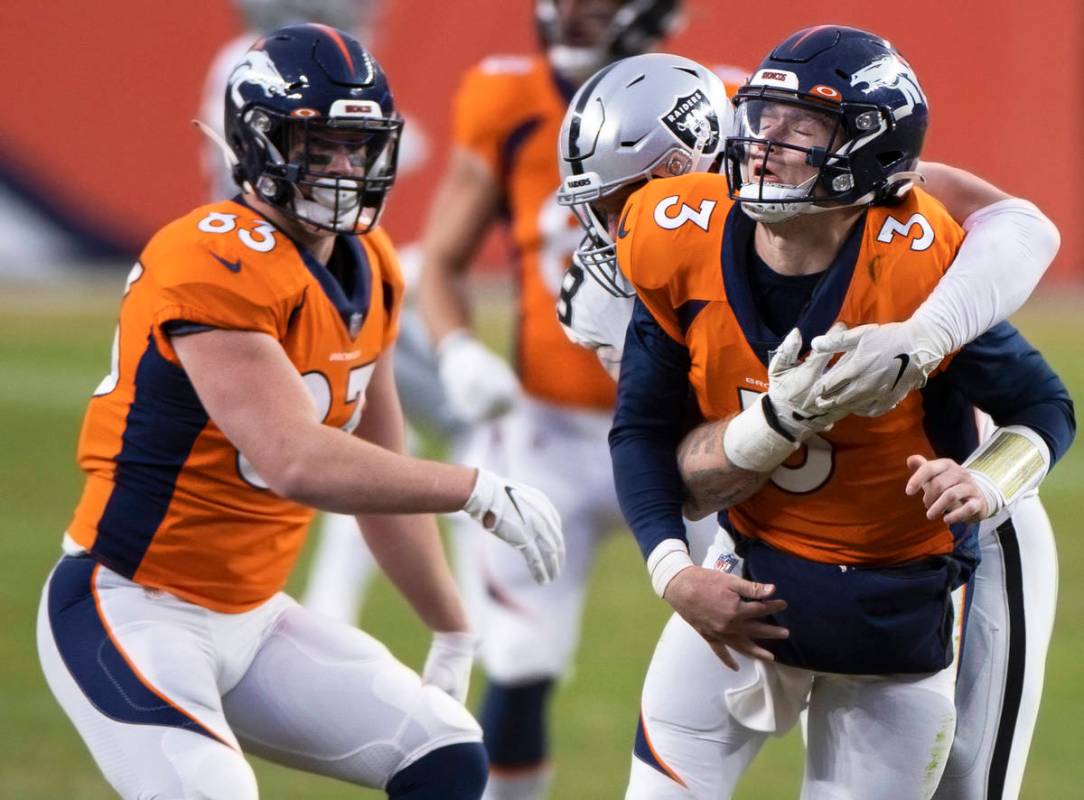Denver Broncos quarterback Drew Lock (3) is hit by Raiders defensive end Maxx Crosby (98) in th ...