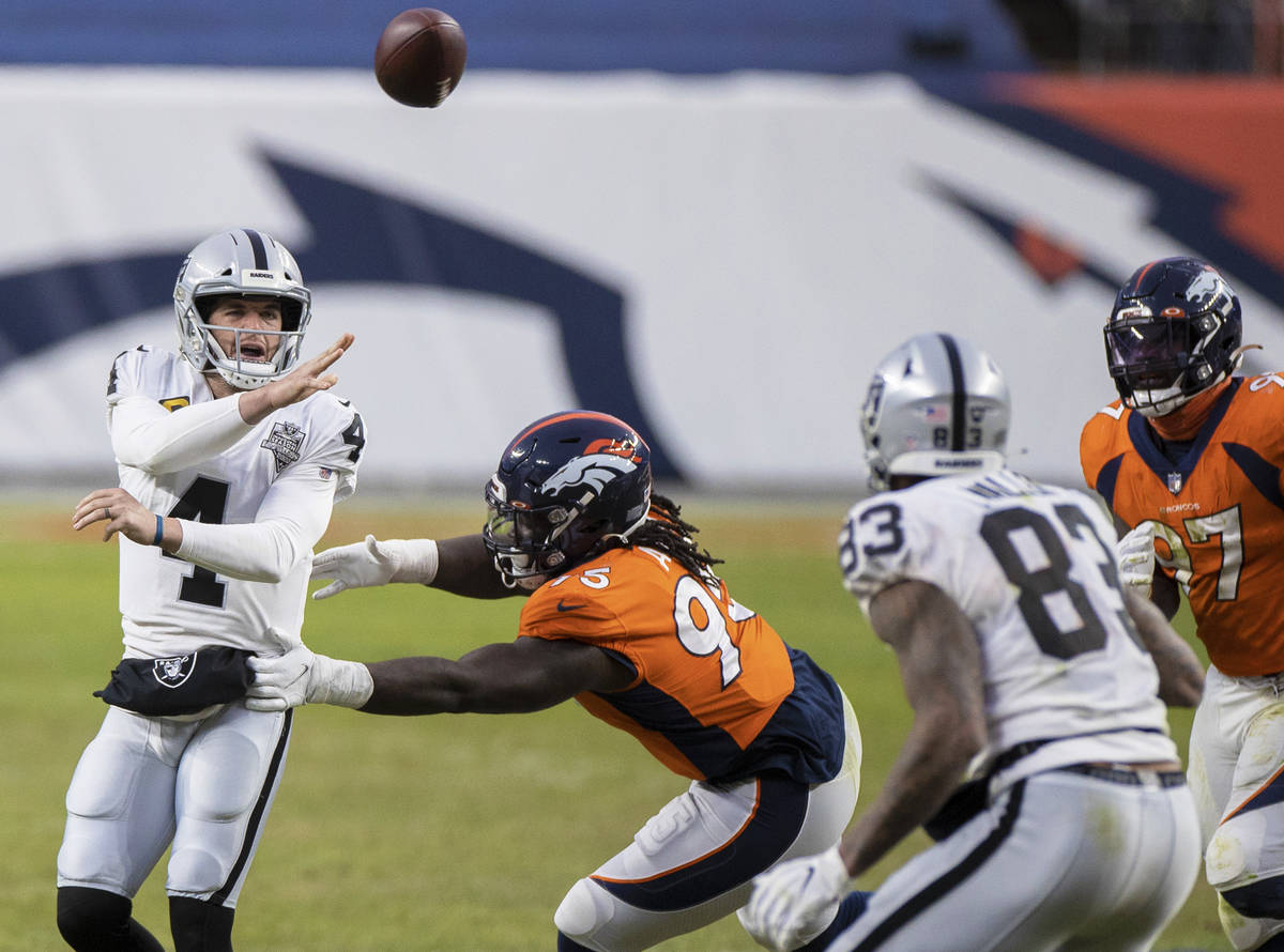 Raiders quarterback Derek Carr (4) just gets a pass away with pressure from Denver Broncos defe ...