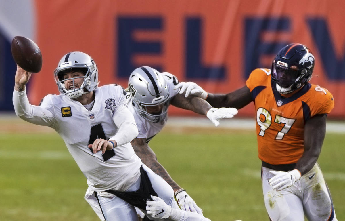 Raiders quarterback Derek Carr (4) just gets a pass away with pressure from Denver Broncos outs ...