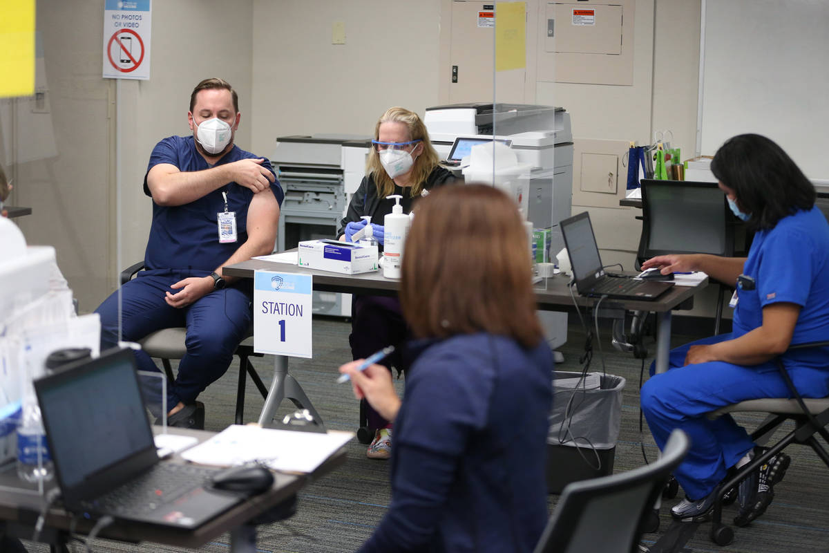 Dr. Rusty Walker, left, wait to receive the second dose of the Pfizer COVID-19 vaccine from Reg ...