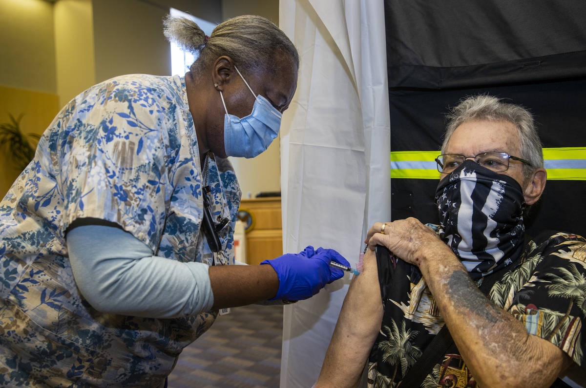 RN Francine Jones-Toliver, left, gives a shot to veteran George Davis as some of the first vete ...