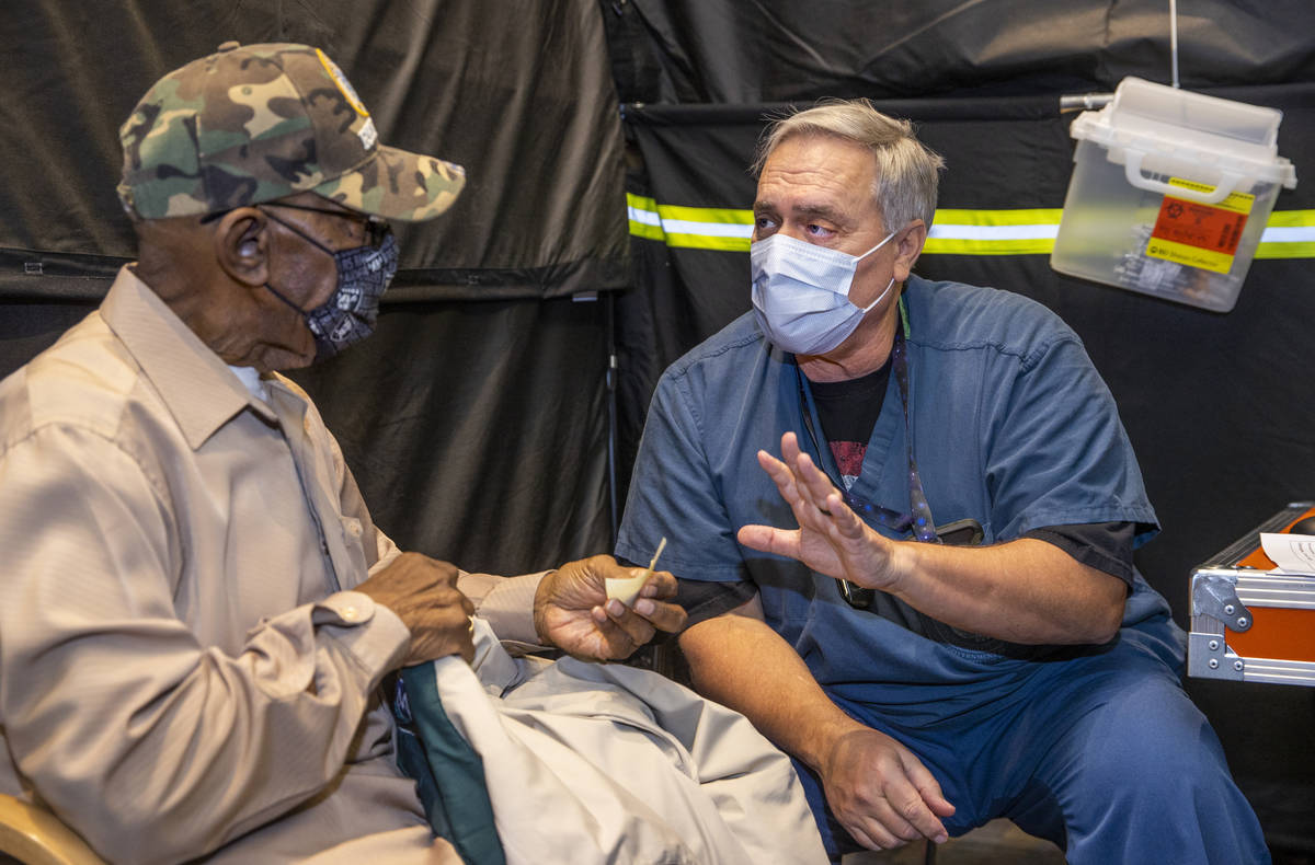 Veteran Mack A. McKinley receives shot follow-up information from RN Darrel Cowlishaw as some o ...