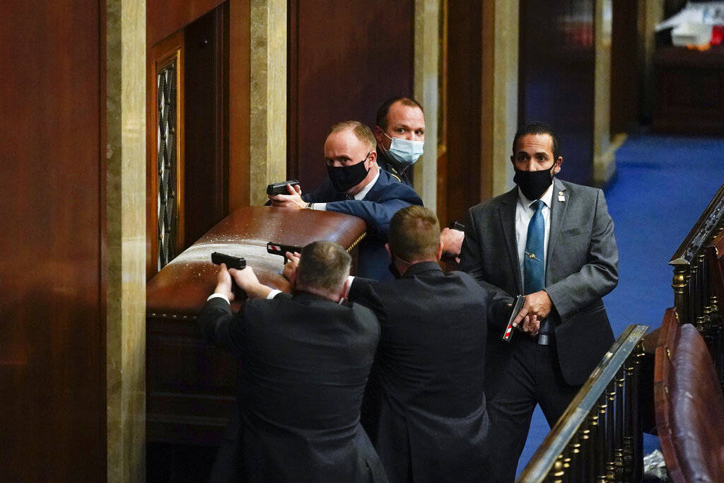 U.S. Capitol Police with guns drawn stand near a barricaded door as protesters try to break int ...