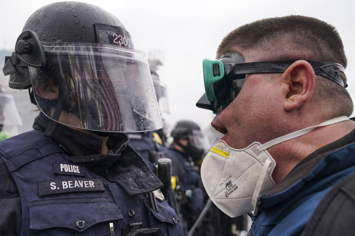 A demonstrator talks to police over a barrier, Wednesday, Jan. 6, 2021, at the Capitol in Washi ...