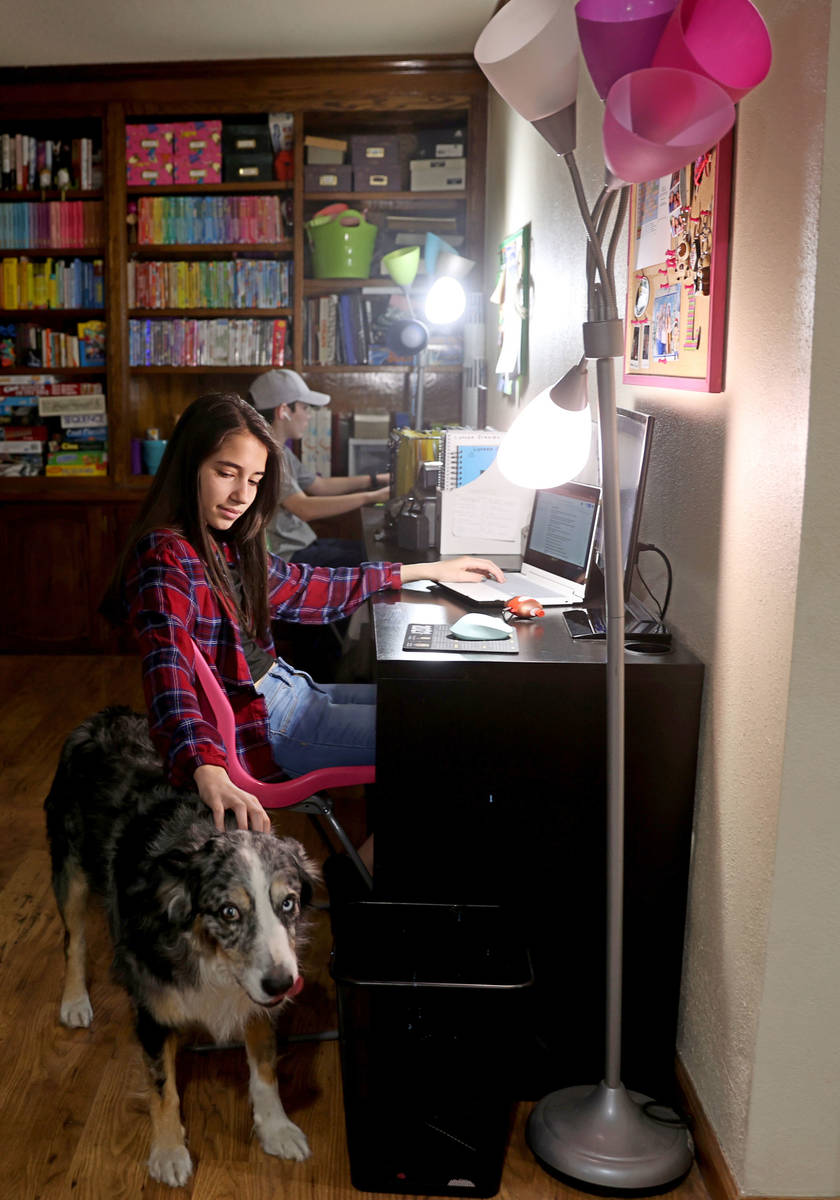 Lynzee Zrebiec, 14, pets her dog Camo who while during distance learning with her twin brother ...