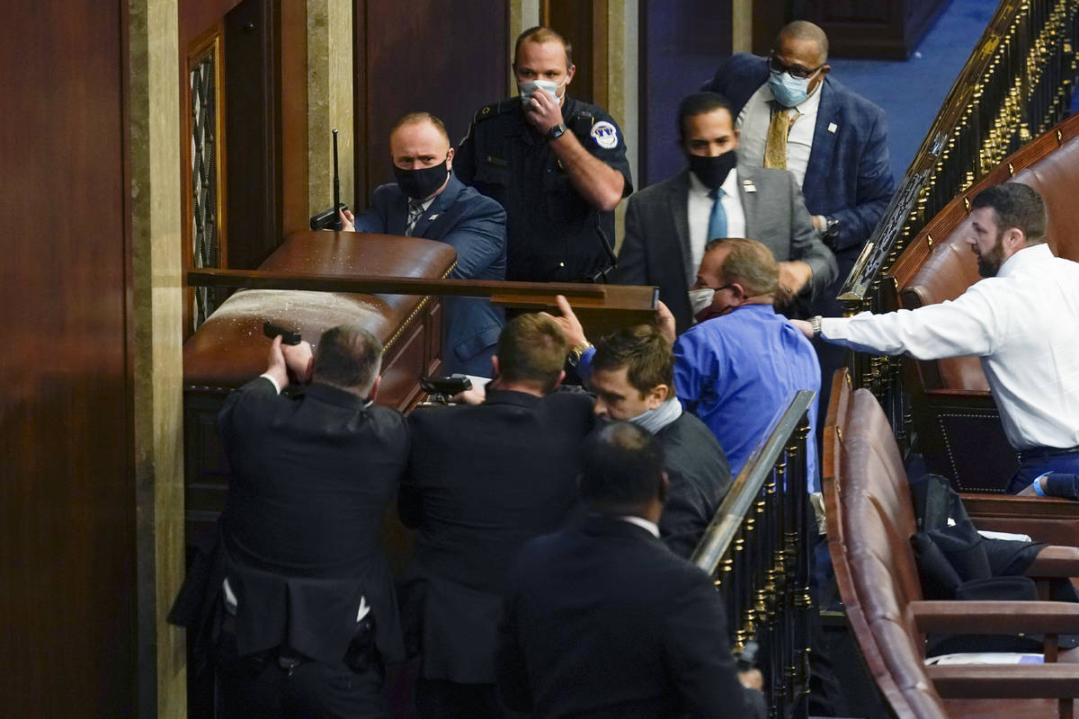 U.S. Capitol Police with guns drawn stand near a barricaded door as protesters try to break int ...