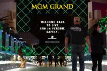An MGM Grand marquee references coronavirus as visitors cross a pedestrian bridge on Monday, No ...