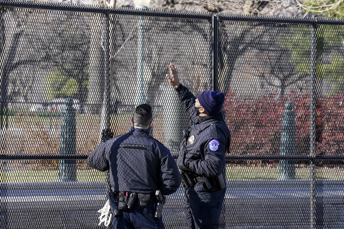 Capitol police officers look at fencing that was installed around the exterior of the Capitol g ...