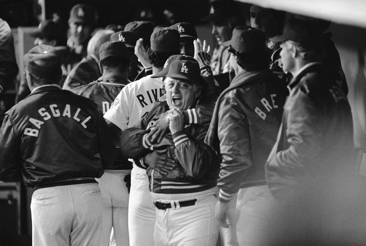 Los Angeles Dodgers manager Tommy Lasorda gets a winning hug from teammate Derrel Thomas, rear, ...