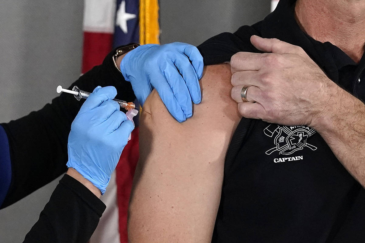 Mesa Fire Department Capt. Jeff Stieber, right, receives the Pfizer-BioNTech vaccine for COVID- ...