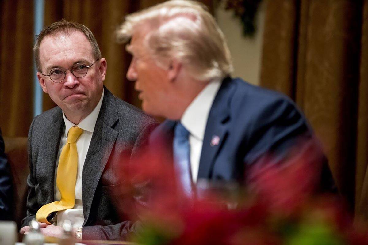In a Dec. 5, 2019, file photo, then-acting chief of staff Mick Mulvaney, left, listens to Presi ...