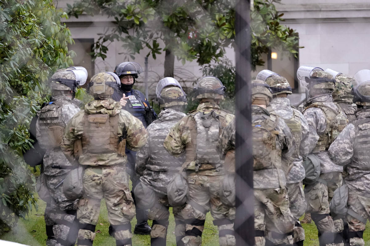 A Washington State Patrol trooper talks with members of the Washington National Guard inside a ...