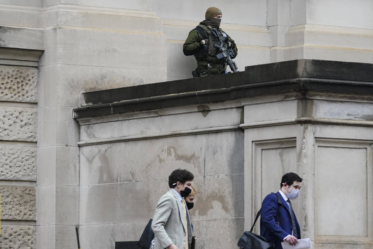 A member of the Georgia State Patrol SWAT team looks on as people walk by outside of the Georgi ...