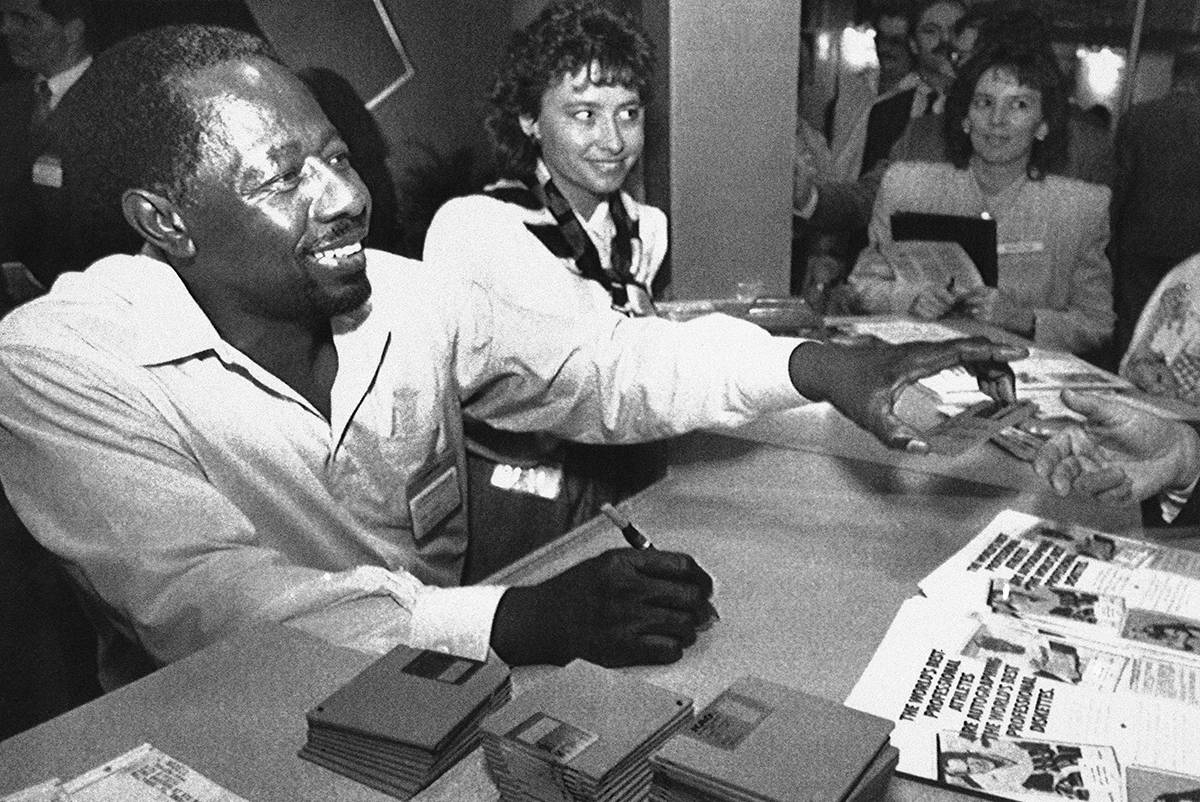Former baseball great Henry Aaron signs autographs on computer disks at the Comdex computer sho ...