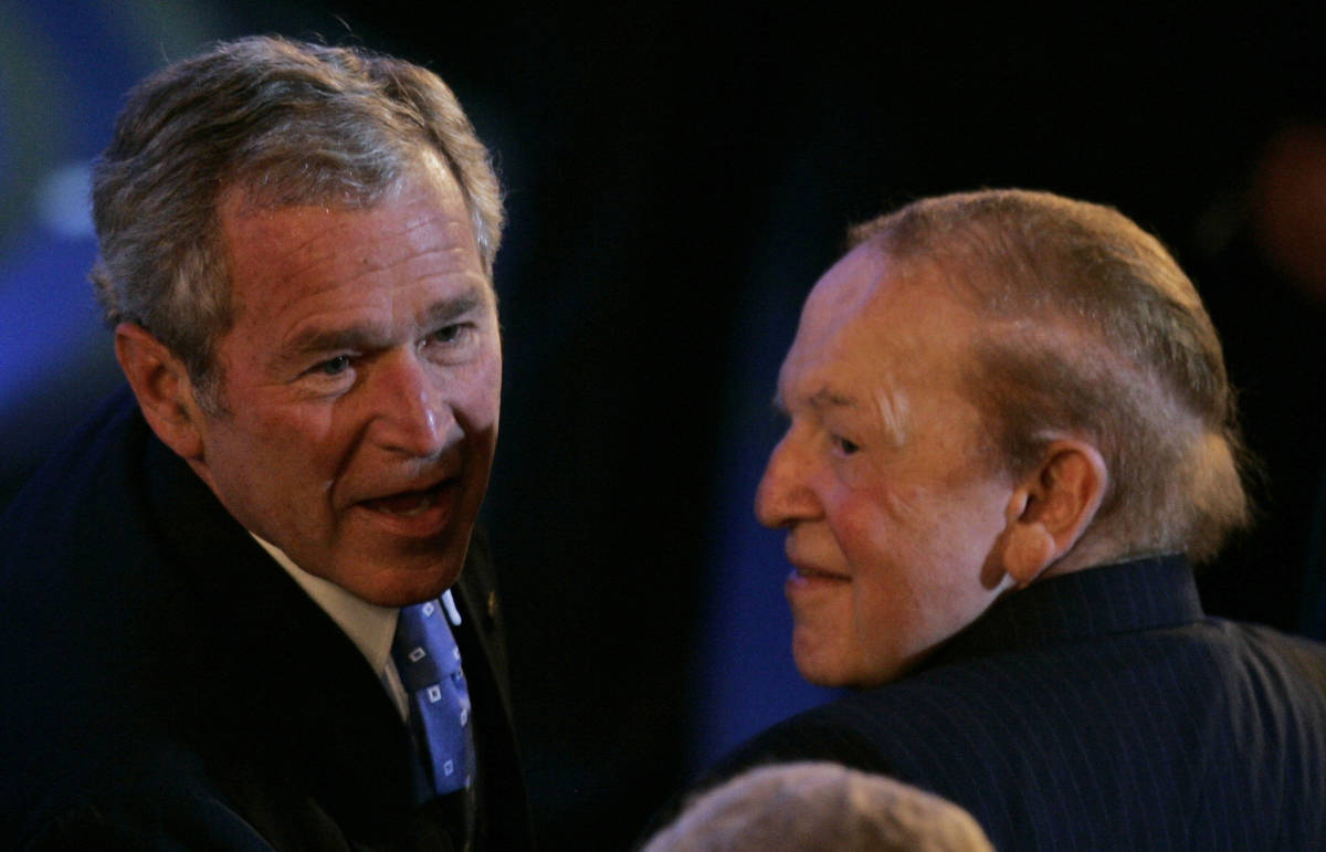 U.S. president George W. Bush, left, sits next to American businessman Sheldon Adelson, right, ...