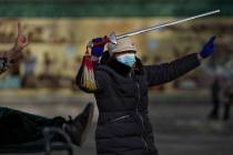 A woman wearing a face mask to help curb the spread of the coronavirus performs a morning exerc ...