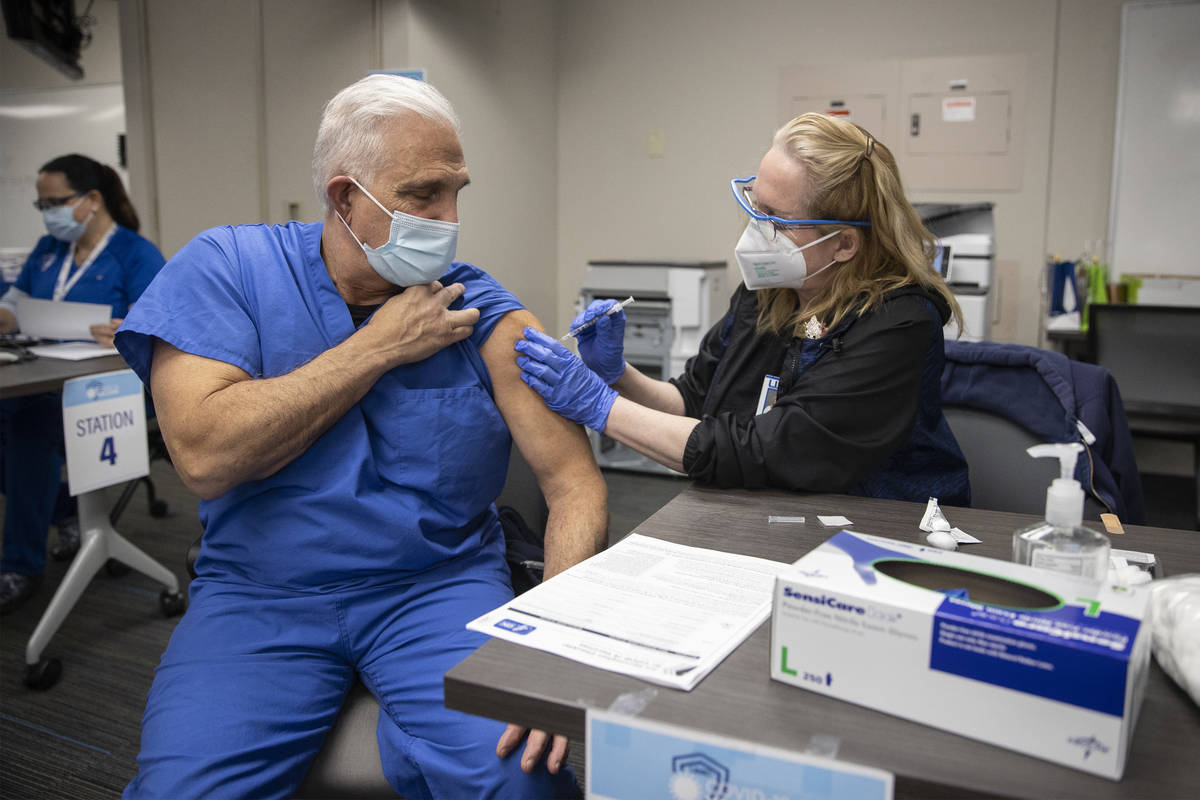 Staff members administer the second dose of the Pfizer COVID-19 vaccine to health workers at UM ...