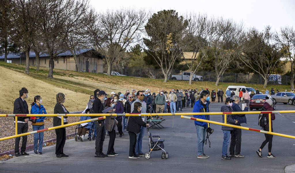 People wait in a long line in the parking lot at the Cashman Center for COVID-19 vaccinations o ...