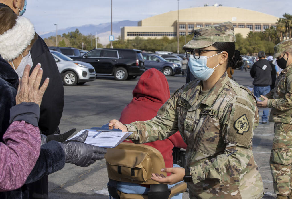 PFC Wendy Garcia passes out paperwork as people wait in line to enter the Cashman Center for CO ...