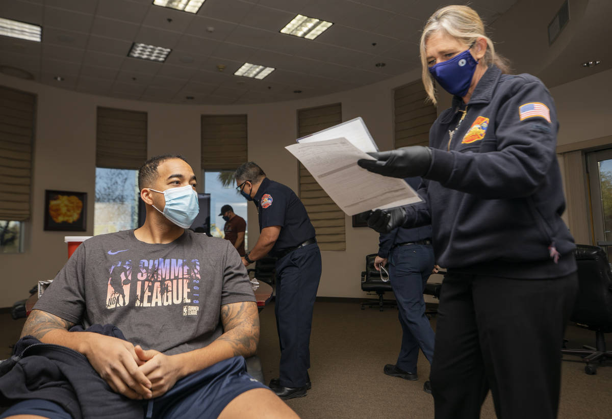 North Las Vegas firefighter Mike Rodgers, 31, left, prepares to receive a COVID-19 vaccine from ...
