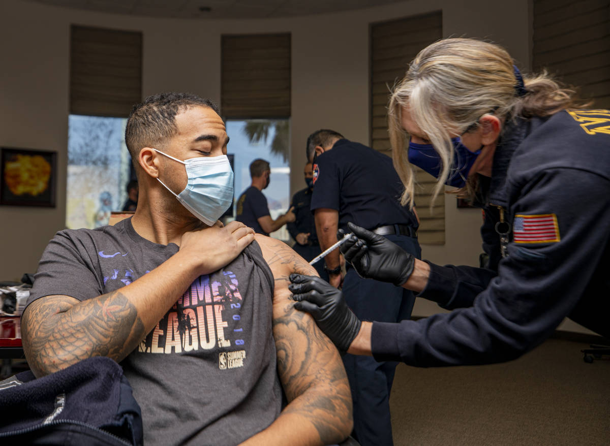 North Las Vegas firefighter Mike Rodgers, 31, left, is administrated a COVID-19 vaccine from em ...