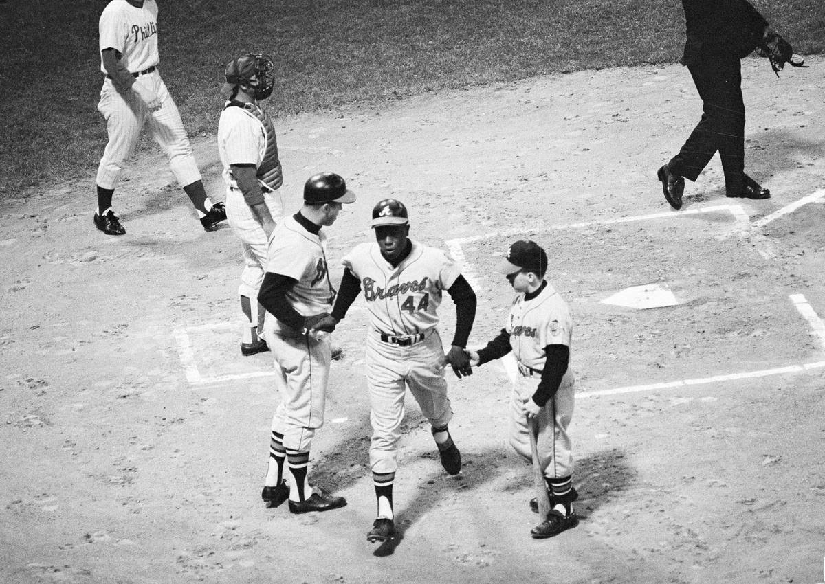 Hank Aaron of the Atlanta Braves is congratulated near home plate by Eddie Mathews and the Brav ...