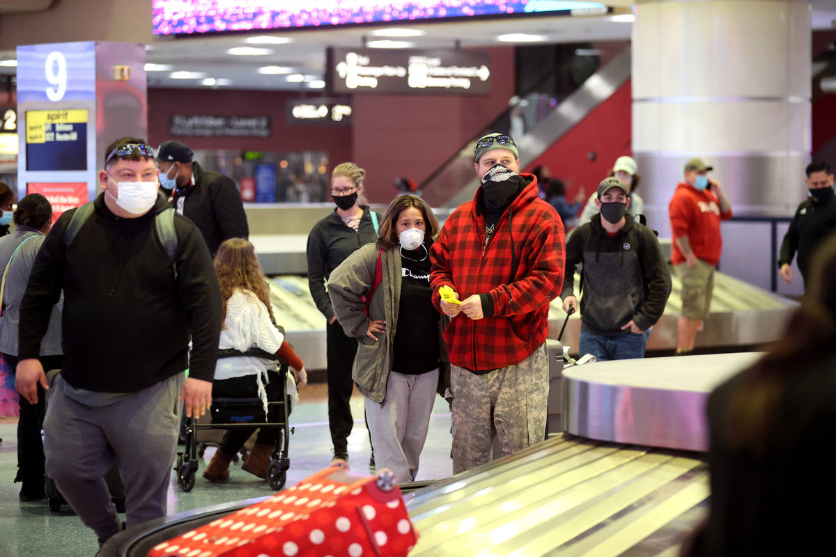 Masked travelers wait to retrieve their luggage in baggage claim Terminal 1 at McCarran Interna ...