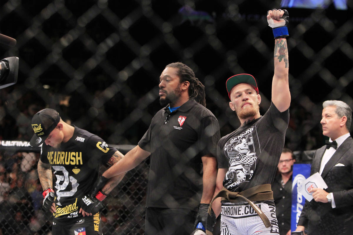 Wearing his new brown belt, Conor McGregor raises his arm after scoring a first round TKO of Du ...