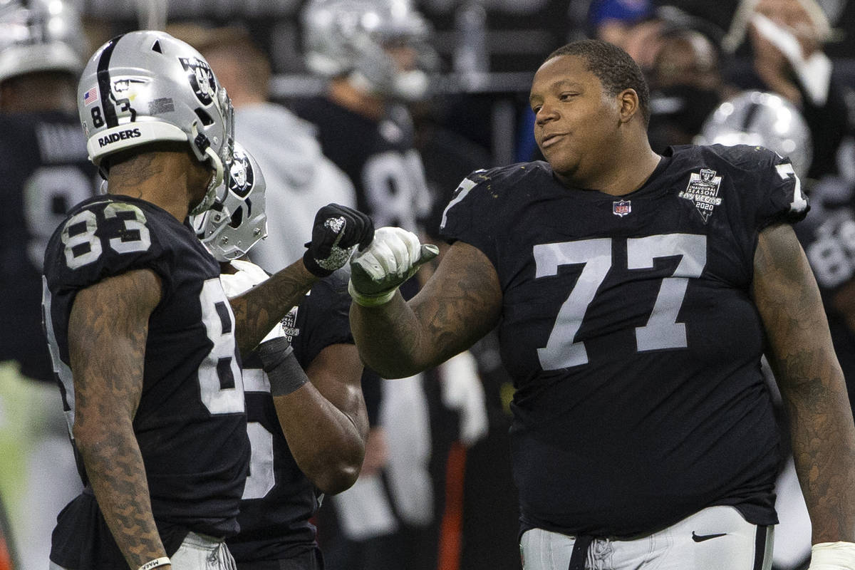 Raiders offensive tackle Trent Brown (77) fist bumps Raiders tight end Darren Waller (83) in th ...