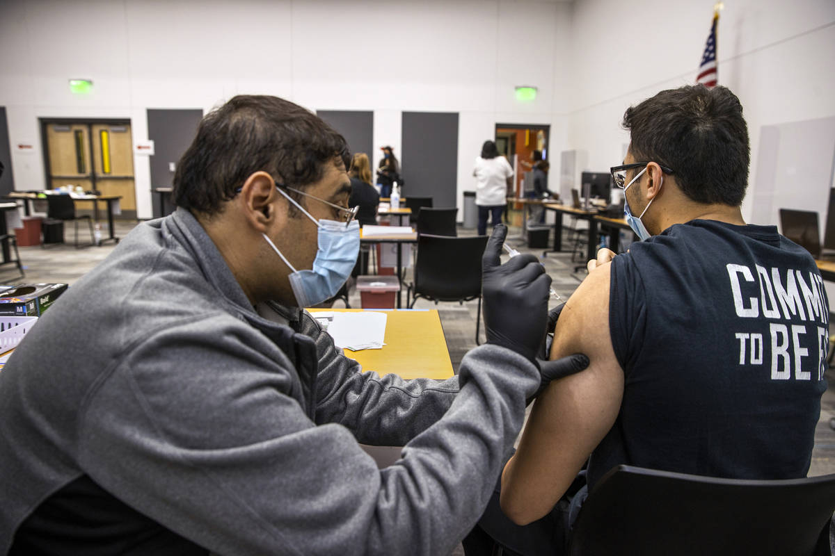 Hugo Peredo, left, with the UNLV School of Medicine, gives a COVID-19 vaccination to CSN studen ...