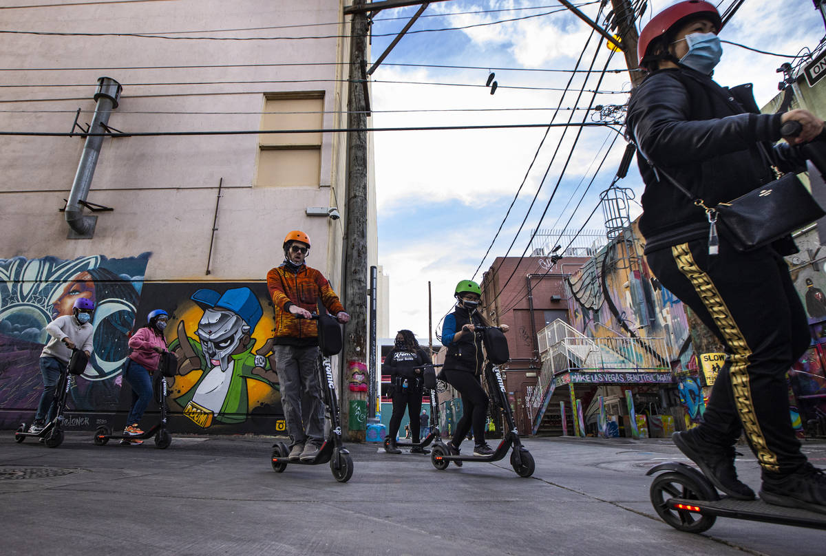 A tour group with Atomic Scooters passes by a new tribute to rapper MF Doom by artist Spen.1 an ...
