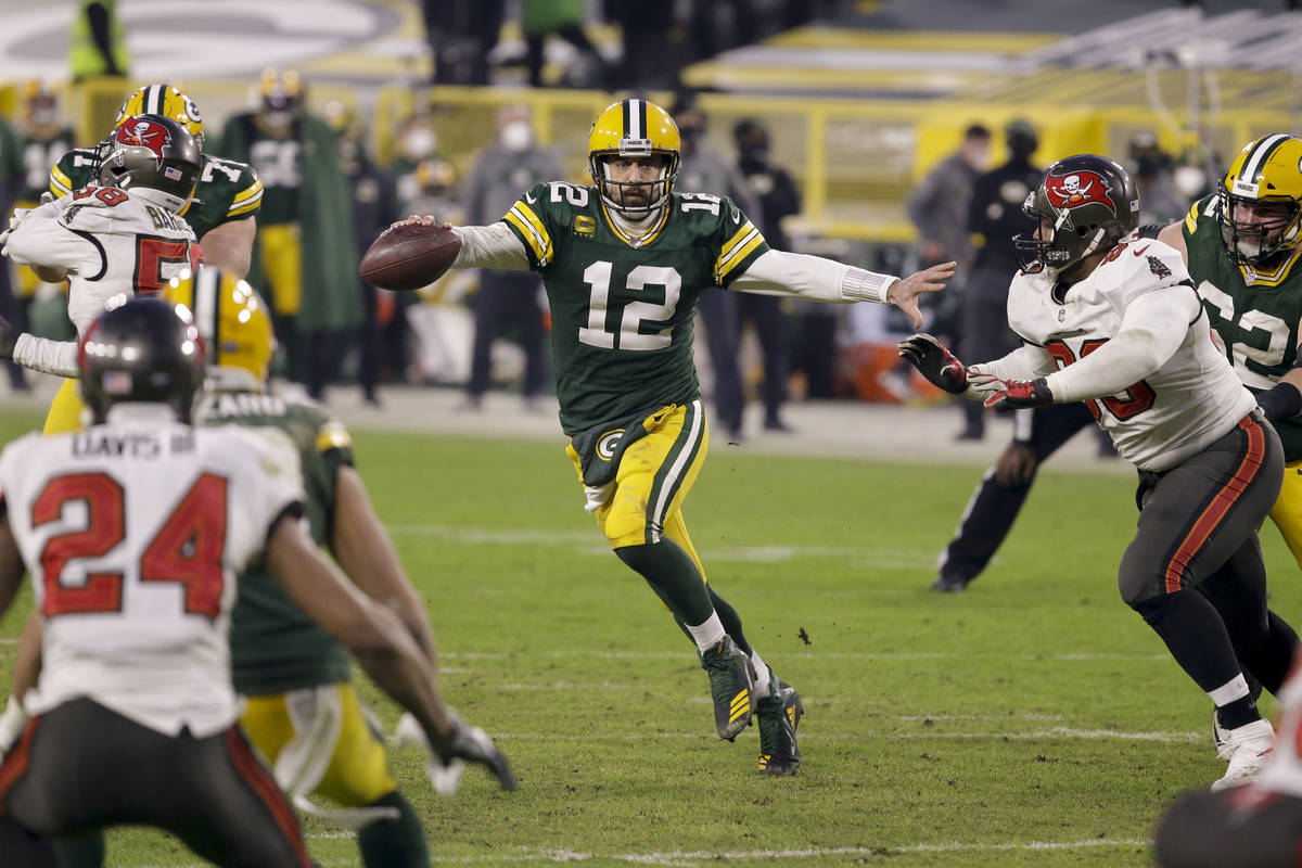 Green Bay Packers quarterback Aaron Rodgers (12) evades a tackle as he looks to pass against th ...
