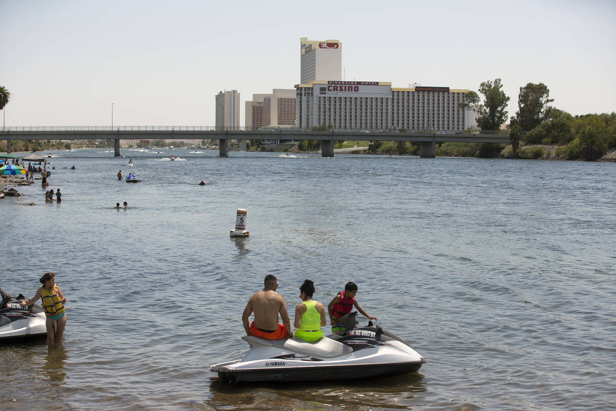 People sit on personal water craft at Davis Camp on the Arizona side of the Colorado River in J ...