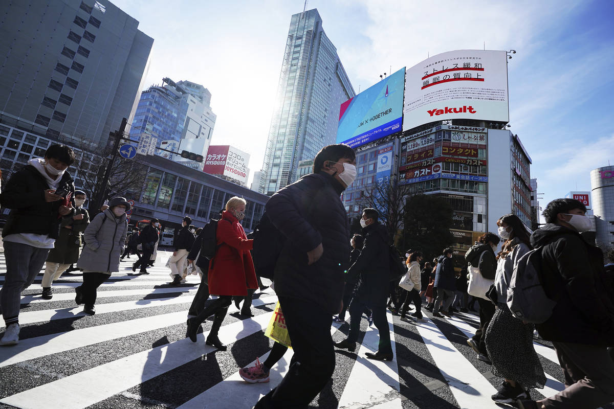 People wearing protective masks to help curb the spread of the coronavirus walk along pedestria ...