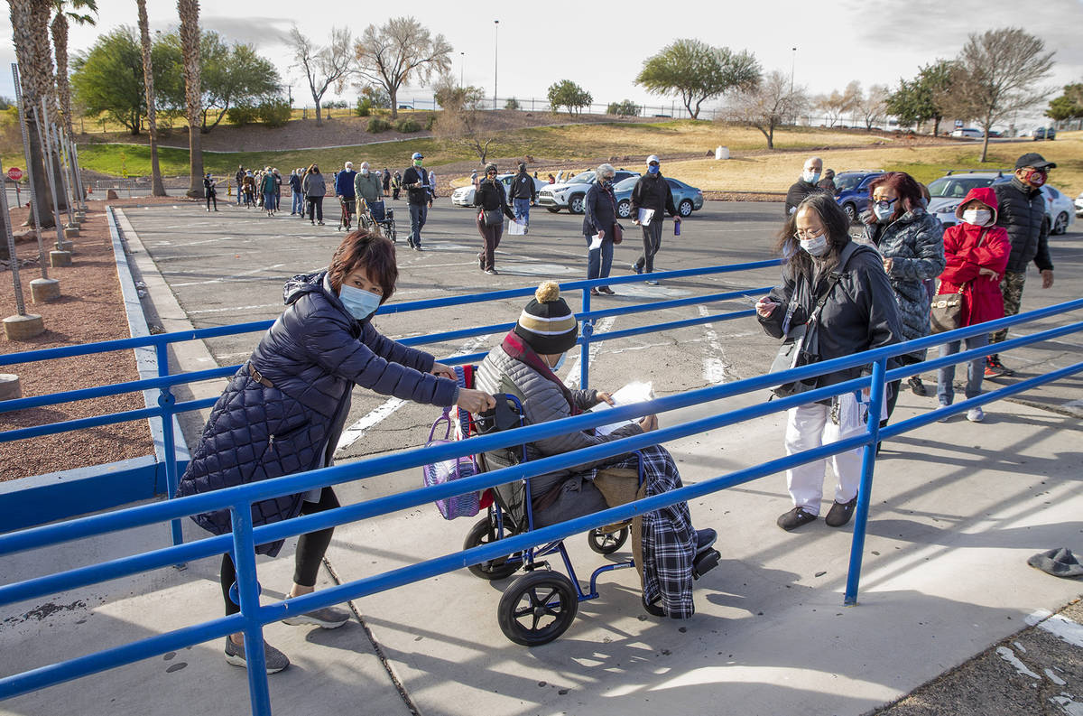 People move along in a long line in the parking lot at the Cashman Center for COVID-19 vaccinat ...