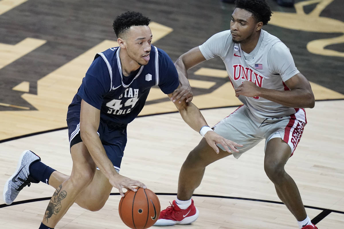 Utah State's Marco Anthony (44) drives into UNLV's Bryce Hamilton (13) during the first half of ...