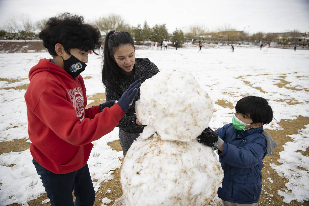 Jenny Lyn Hilario, center, with her sons Gabriel, 12, left, and Isaac, 7, build a snowman at Hu ...