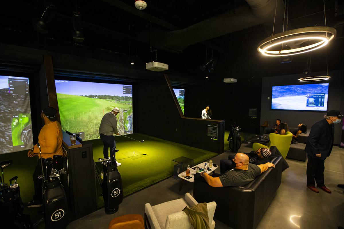 People mingle and take turns playing during a friends and family event at Five Iron Golf at Are ...