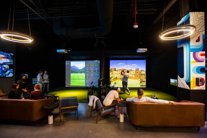 People mingle and take turns playing during a friends and family event at Five Iron Golf at Are ...